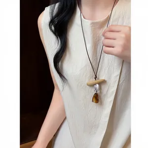 Detailed view of a retro ethnic resin pendant necklace with leather cord worn by a model