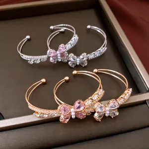 Detailansicht eleganter Schmetterlings-Zirkonia-Armreifen in Gold und Silber mit Perlen.