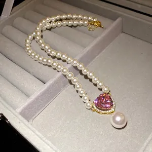 Nahaufnahme eines luxuriösen herzförmigen rosa Zirkon-Anhängers mit Perlenkette.