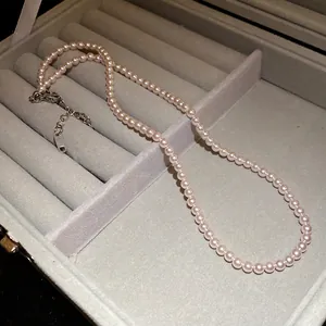 Elegante hellrosa Perlenkette, präsentiert in einer grauen Schmuckschatulle.