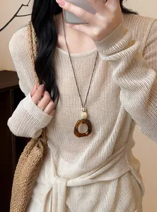 Detail of vintage resin oval pendant necklace on long leather cord with beige sweater