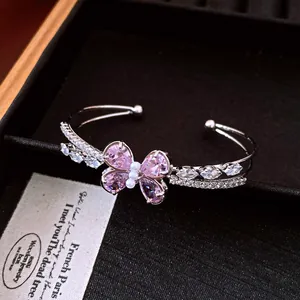 Detaillierte Nahaufnahme eines eleganten silbernen Armreifs mit rosa Zirkonia-Schmetterling.