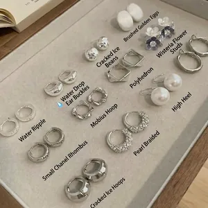 Surtido de pendientes minimalistas de metal plateado y perlas en bandeja