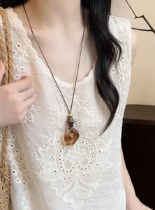 Detailed view of a vintage amber resin pendant necklace with ethnic style cord