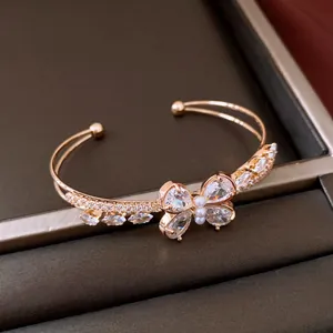 Detailaufnahme eines eleganten Goldarmreifs mit einem Zirkonia-Schmetterling und Perle