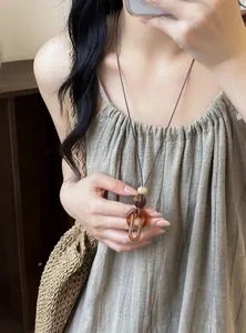 Close-up detail of a vintage resin oval pendant necklace with a leather cord on model