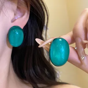 Detailed shot of large oval emerald green resin stud earrings with pearlescent glow