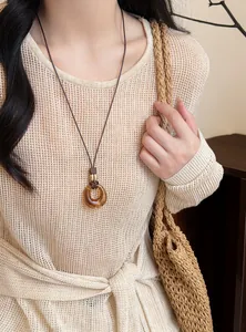 Detail of retro resin oval pendant necklace on brown leather cord worn by model