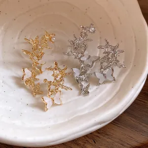 Detailed view of asymmetric gold and silver butterfly ear clips with pearl accents.