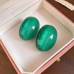 Close-up view of elegant green oval resin stud earrings with cat-eye luster inside a jewelry box