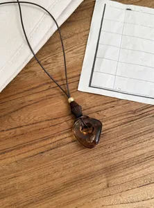 Macro detail view of the retro amber resin pendant on a brown leather cord necklace.