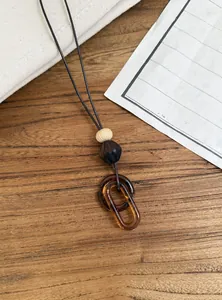 Close-up detail of interlocking amber resin oval rings on a vintage leather cord necklace.