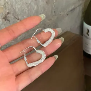 Detailed close-up of elegant silver heart hoop earrings decorated with tiny white pearls