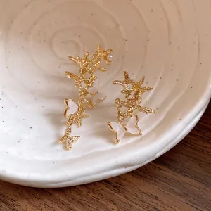 Close-up of elegant asymmetric gold butterfly ear cuffs with exquisite shell-like acetate details.