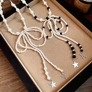 Vintage French style stainless steel bow pearl necklace with star pendants on a jewelry tray