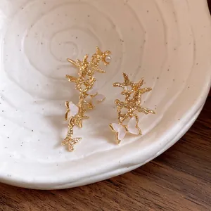 Close-up detail of asymmetric gold butterfly ear cuffs displayed on a ceramic dish.