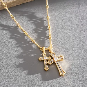Detailed view of a gold-plated double cross necklace with shimmering zircon stones.