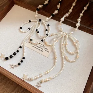 Detail view of pearl bow tassel necklace with stainless steel star charms