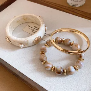 Detail of vintage resin marble bangle and gold metal bracelet set with shell accents.
