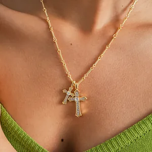 Close-up of gold double cross pendant necklace with zircon stones on model's neck