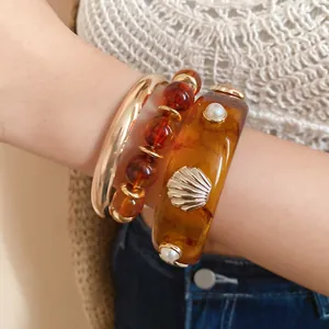 Macro detail shot of a vintage resin shell bracelet set featuring a gold metal bangle.
