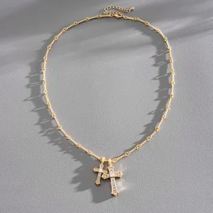 Detailed macro view of gold-tone double cross necklace with shimmering zirconia stones