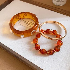 Set of vintage amber resin and gold-tone bracelets with elegant shell and pearl details.