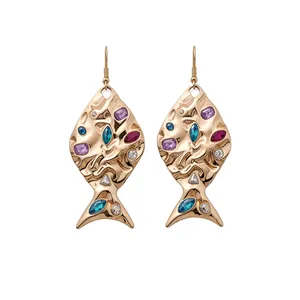 Eleganti orecchini a forma di pesce dorati con strass colorati su sfondo bianco