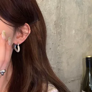 Close-up view of elegant silver heart-shaped hoop earrings decorated with pearls on ear