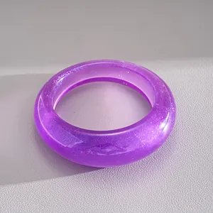 Dettaglio di un bracciale rigido in acrilico viola traslucido con glitter argento interni.