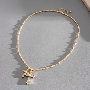 Detailed view of a gold-tone necklace featuring two pavé-set zircon cross pendants.