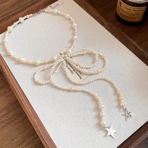 Detailed view of a vintage-style pearl bow necklace with star pendants on a wooden tray.