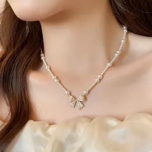 Elegant French style pearl necklace featuring a gold zircon bow pendant on model neck