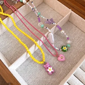 Colorful beaded necklaces with bear, heart, and butterfly charms in a jewelry box