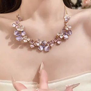 Detailansicht einer eleganten Halskette mit lila Emaille-Blüten an einem Modell.