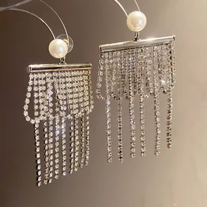 Détail de boucles d'oreilles à pampilles argentées avec perles et strass brillants