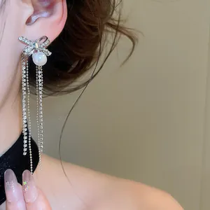 Close-up of elegant zircon bow-knot tassel earrings with a white pearl drop