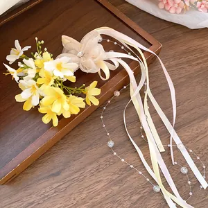 Detail view of a floral hair clip with colorful ribbons and pearl beads on a wooden tray