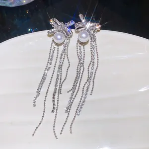 Detailed macro shot of silver bow knot tassel earrings with pearls and zircons.