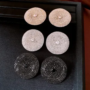 Vista dettagliata di orecchini a bottone tondi con strass in oro, argento e nero