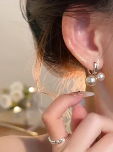 Primer plano de pendientes de aro vintage con doble perla con luz cálida y elegante