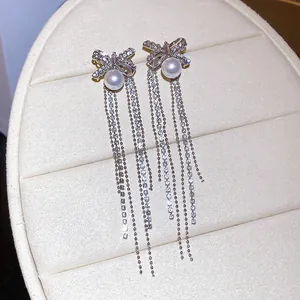 Detailed view of elegant silver bow tassel earrings with sparkling zircons and pearls