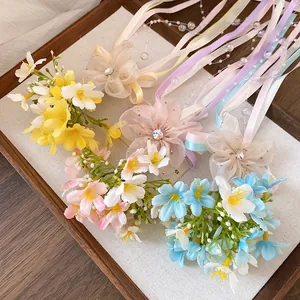 Detail view of colorful forest-style flower hair clips with long ribbons in a wooden tray