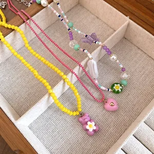 Detail shot of colorful resin butterfly and bear pendant necklaces in a wooden jewelry box
