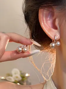 Primer plano de pendientes de aro con perlas en forma de cereza con iluminación cálida