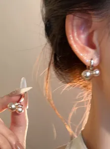 Vista detallada de pendientes de aro con perlas francesas vintage en la oreja y mano