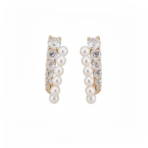 Elegant gold earrings with clear zircons and white pearls in a curved design