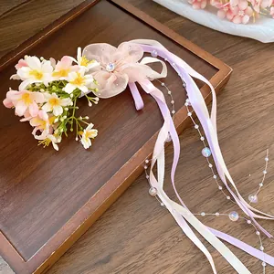 Detail view of a Moriy-style flower hair clip with pastel ribbons and pearly beads