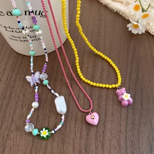 Close-up of colorful resin necklaces with heart, butterfly and bear pendants on wood.