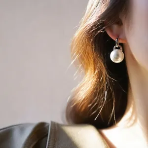 Primo piano di un elegante orecchino di perla bianca in stile francese su un modello